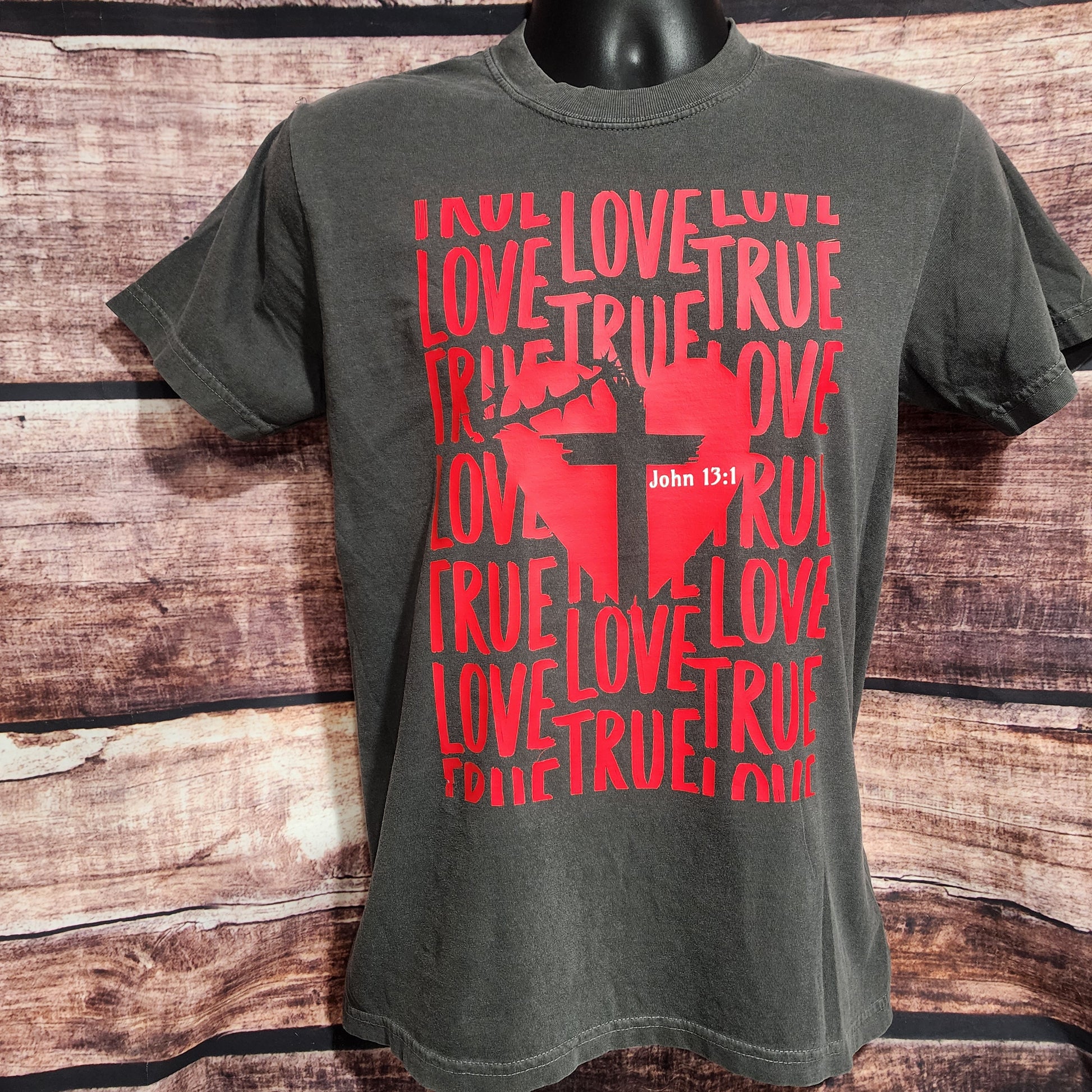 Gray t-shirt with red graphic and text on a wooden surface