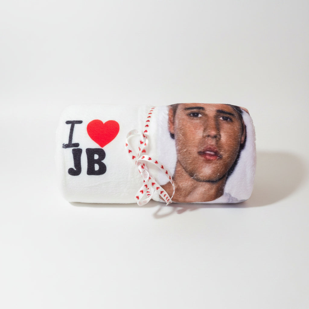A custom white plush blanket featuring a printed portrait of a man, with 'I' and 'JB' in black letters and a red heart symbol, tied with a red and white heart-patterned ribbon.