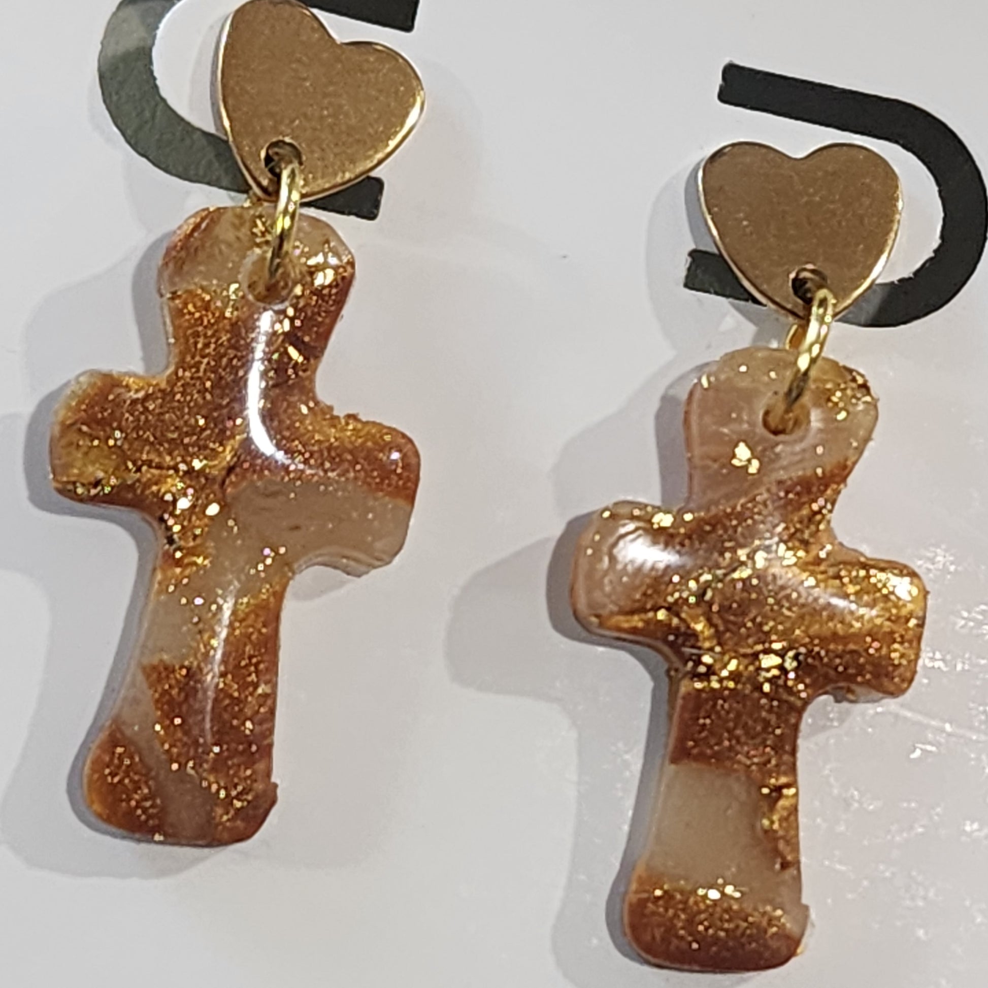 Gold glittery cross-shaped earrings on a white background
