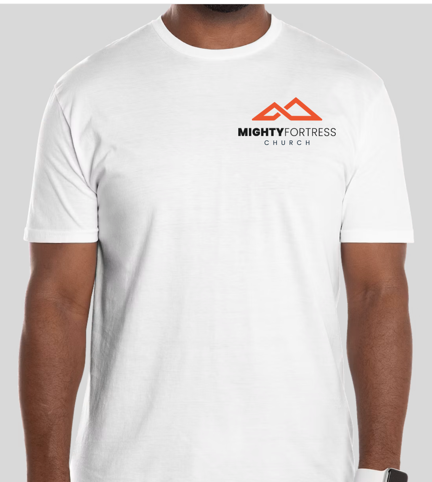 A white short-sleeve crewneck t-shirt with a 'MIGHTY FORTRESS CHURCH' logo printed on the left chest, worn by a model against a light gray background.