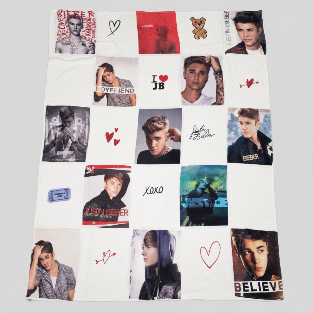 A white  blanket featuring a collage of Justin Bieber photos, handwritten notes, and small red heart drawings, laid flat on a gray carpet.