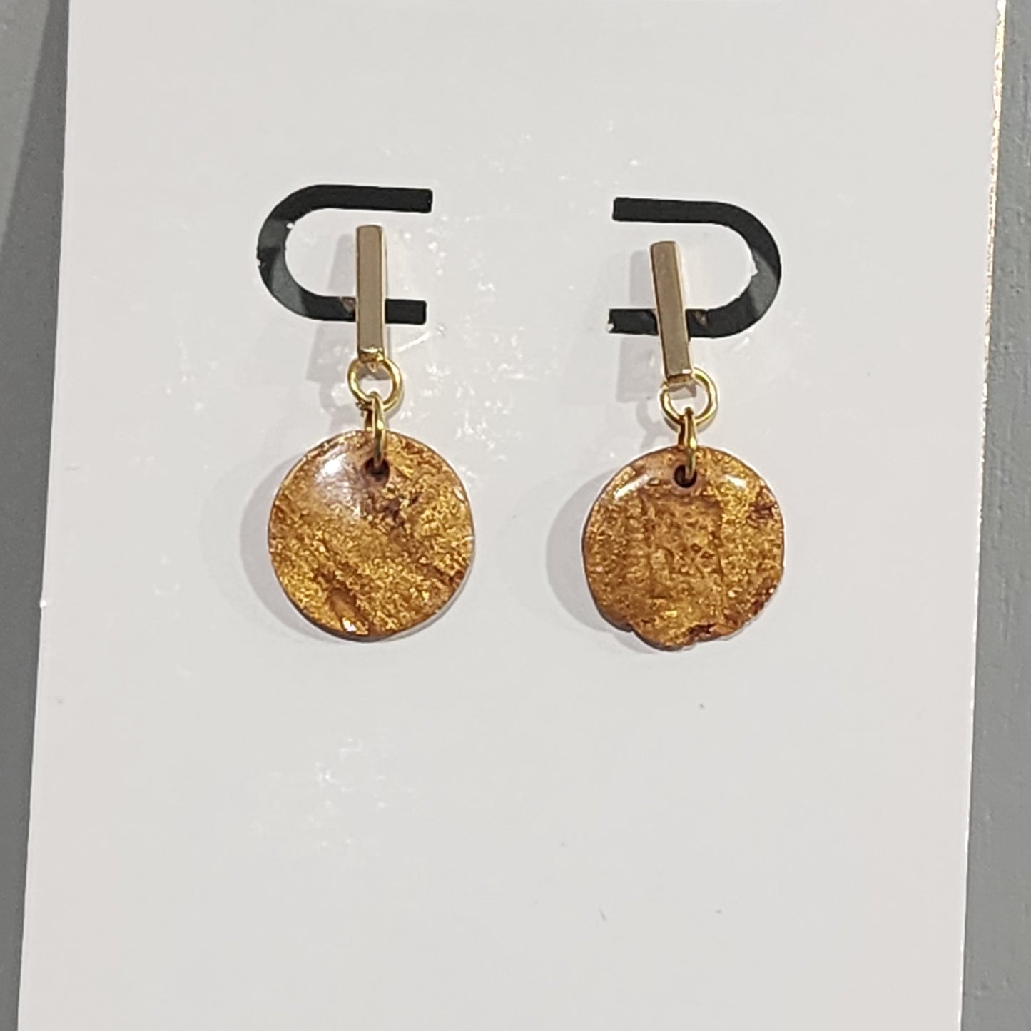 Gold disc earrings on a white card with a brand logo.